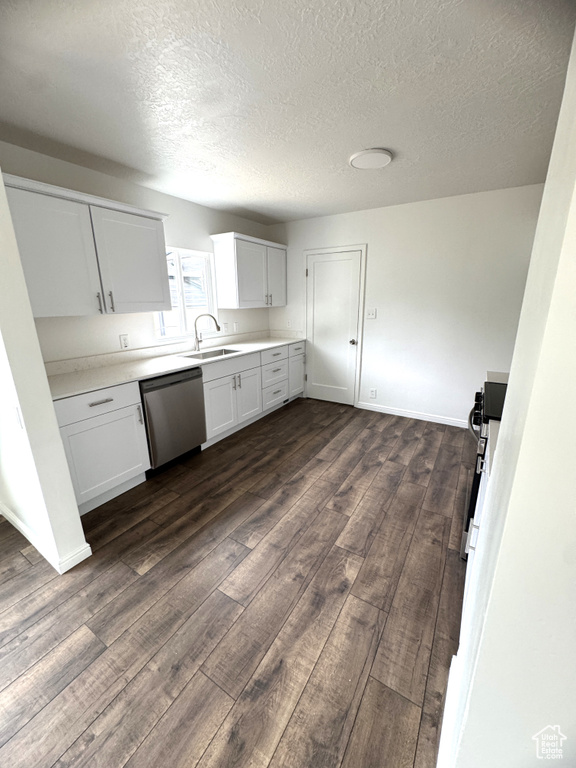Kitchen featuring appliances with stainless steel finishes, dark wood finished floors, a textured ceiling, light countertops, and white cabinets