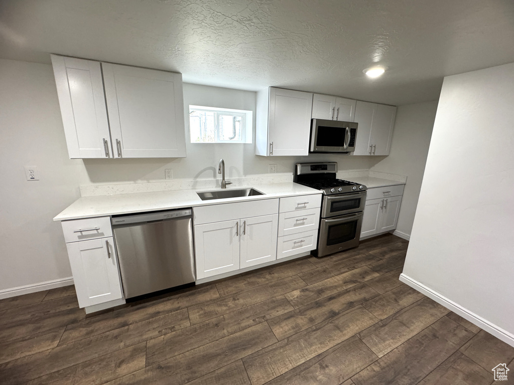 Kitchen with stainless steel appliances, dark wood-style floors, and white cabinets