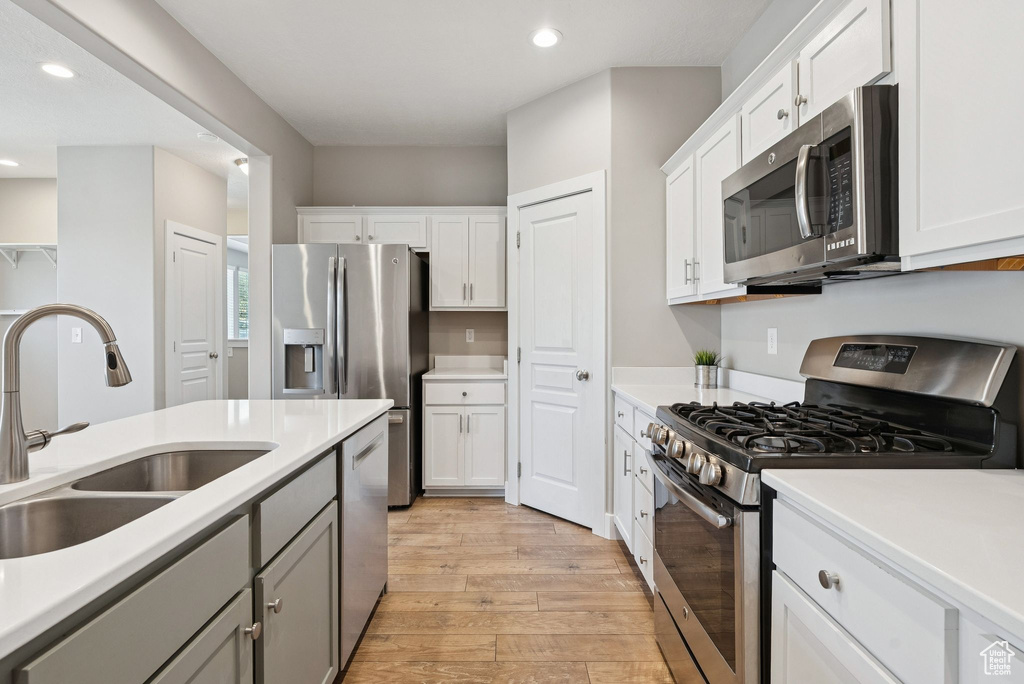 Kitchen featuring appliances with stainless steel finishes, light wood-type flooring, recessed lighting, light countertops, and white cabinets