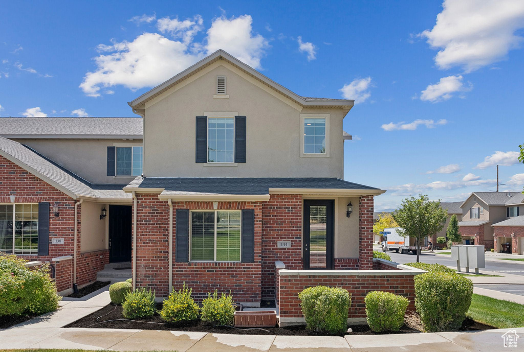 Traditional-style home featuring brick siding, stucco siding, and a shingled roof