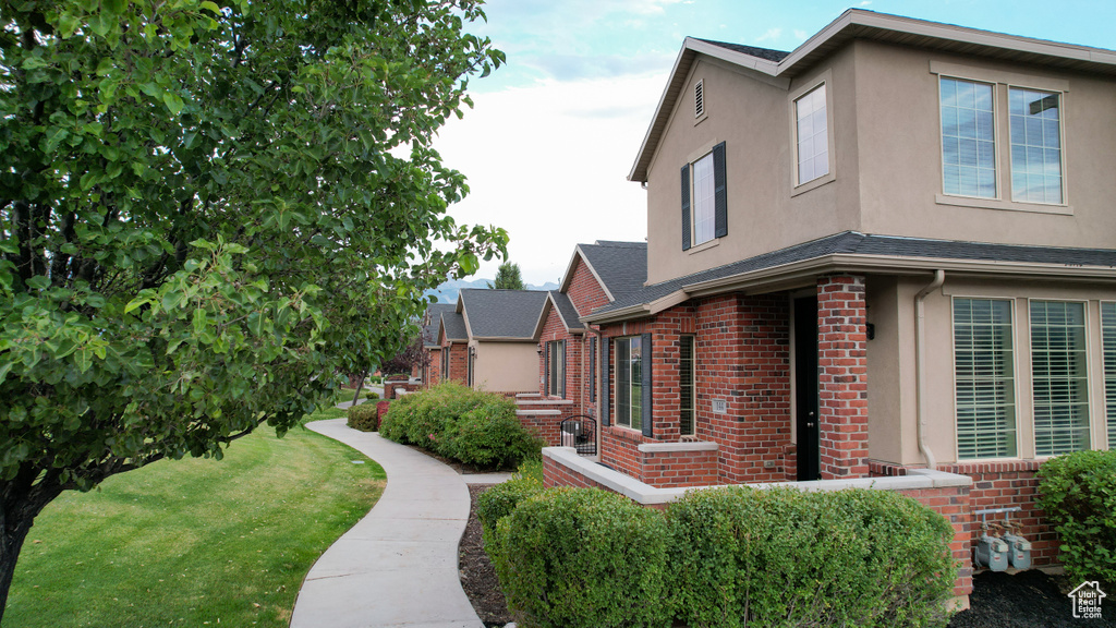 View of side of property with brick siding, stucco siding, and a lawn