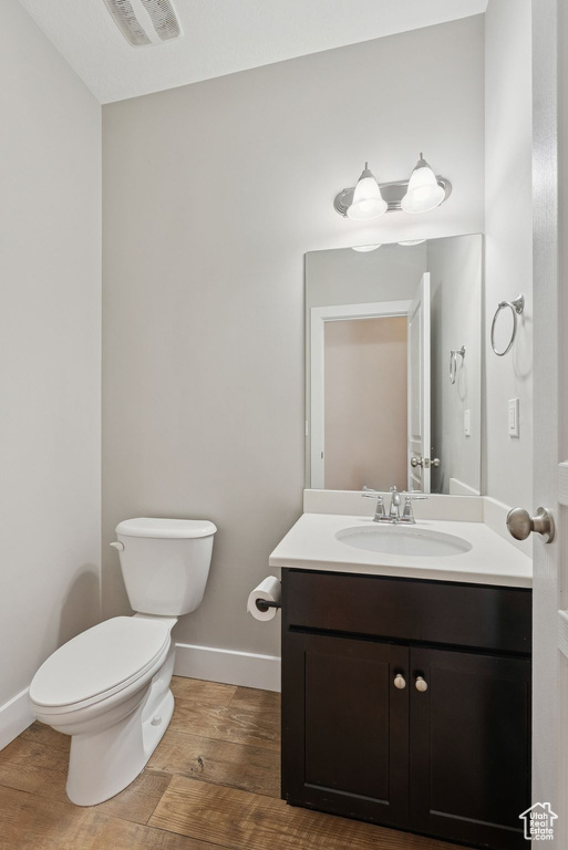 Half bath with vanity and wood finished floors