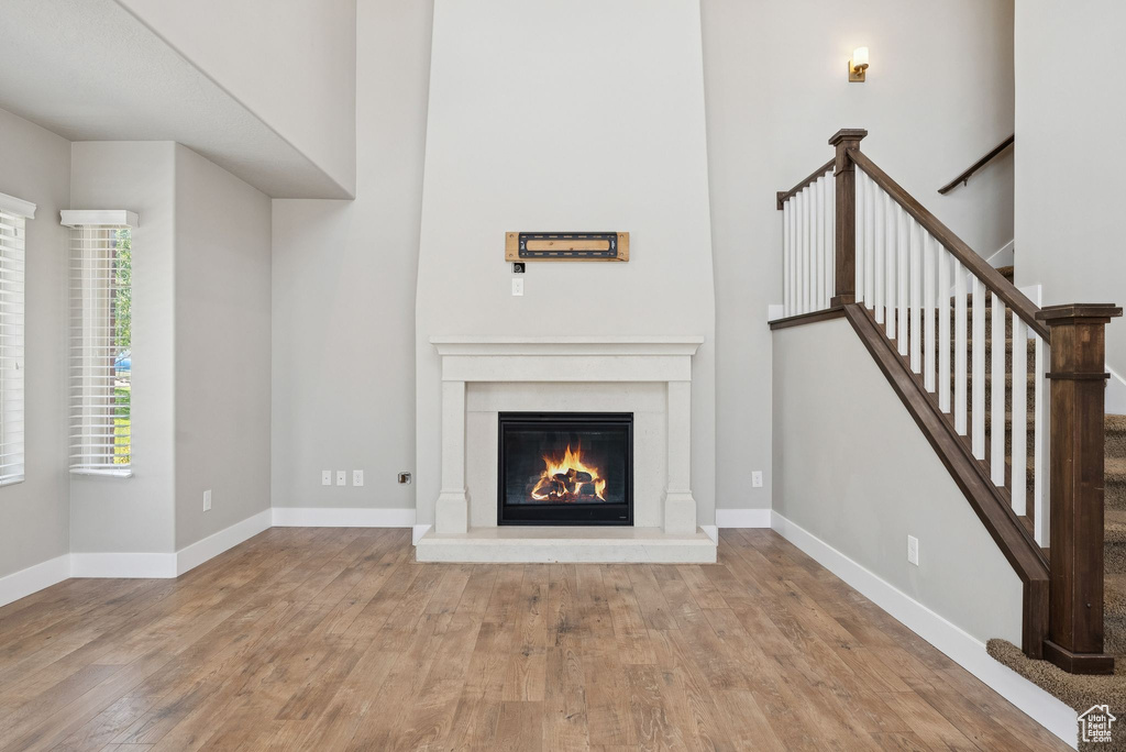 Unfurnished living room with wood finished floors, a glass covered fireplace, and stairs