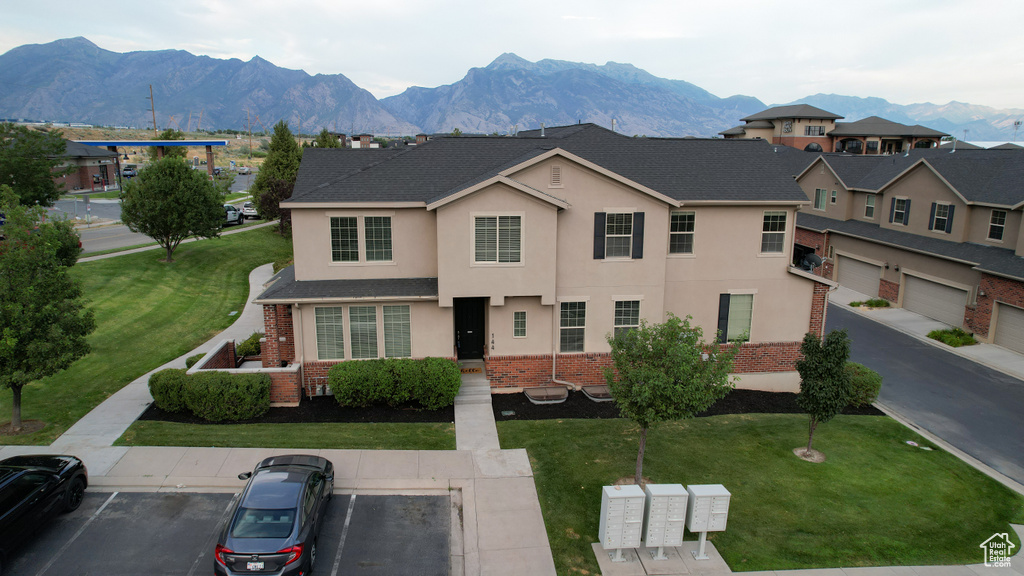 View of front of house with stucco siding, a mountain view, uncovered parking, and brick siding