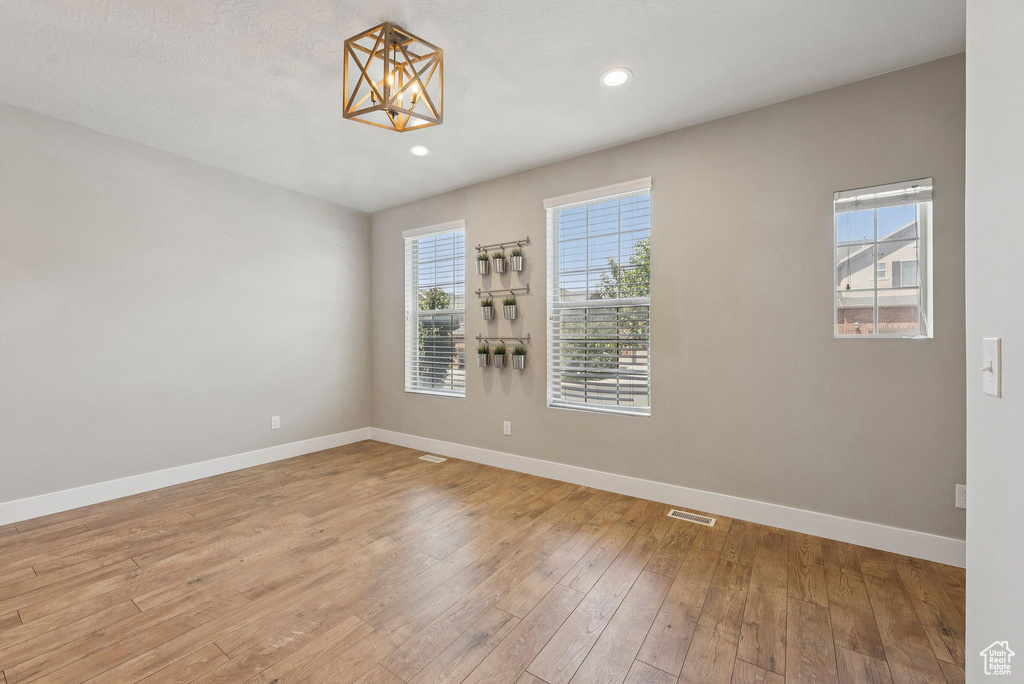 Spare room with light wood-style floors, a chandelier, and recessed lighting