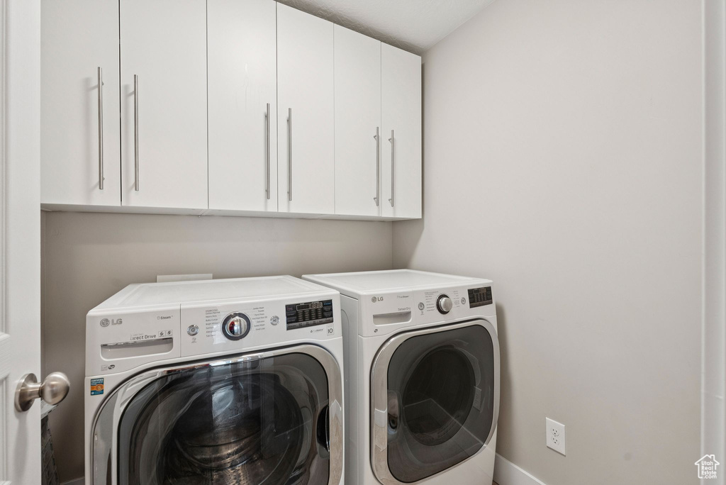 Laundry room featuring washing machine and clothes dryer and cabinet space
