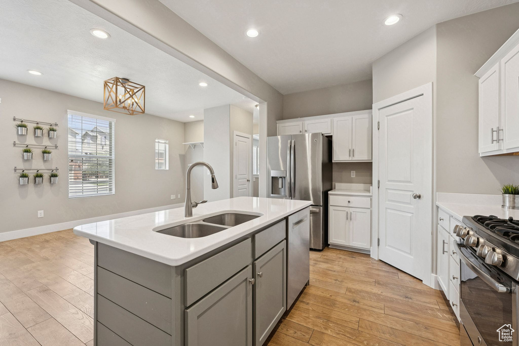 Kitchen featuring stainless steel appliances, gray cabinets, light countertops, light wood-type flooring, and recessed lighting