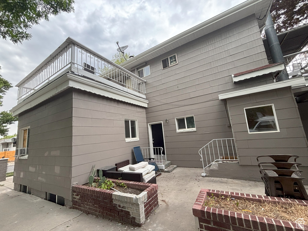 Back of property with a balcony and a patio