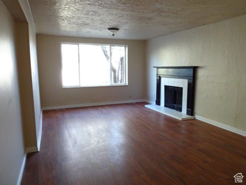 Unfurnished living room with wood finished floors, a fireplace, and a textured ceiling