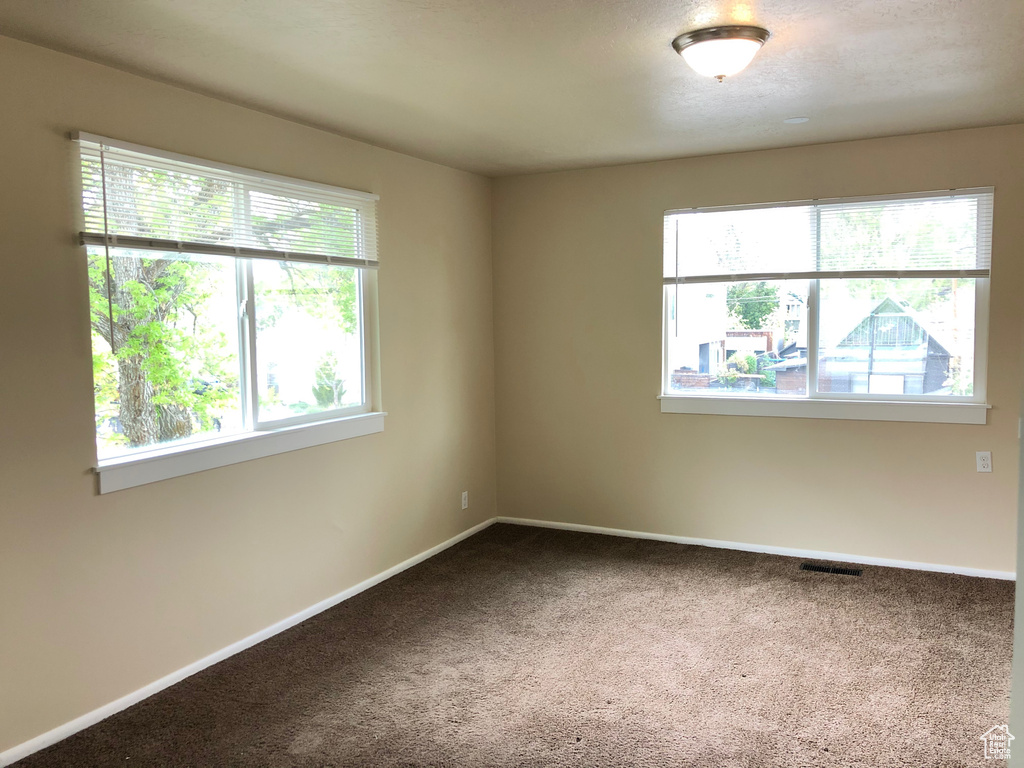 Carpeted spare room featuring baseboards