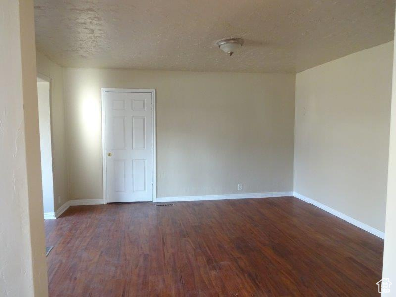 Unfurnished room with dark wood finished floors and a textured ceiling