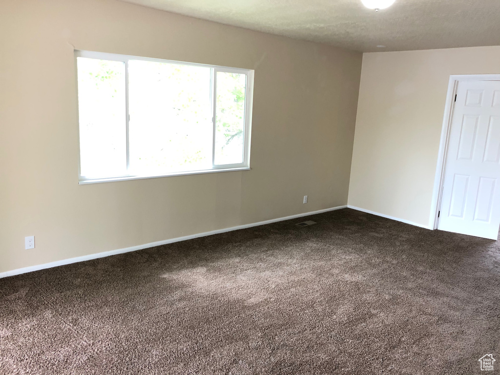 Empty room with dark carpet and healthy amount of natural light