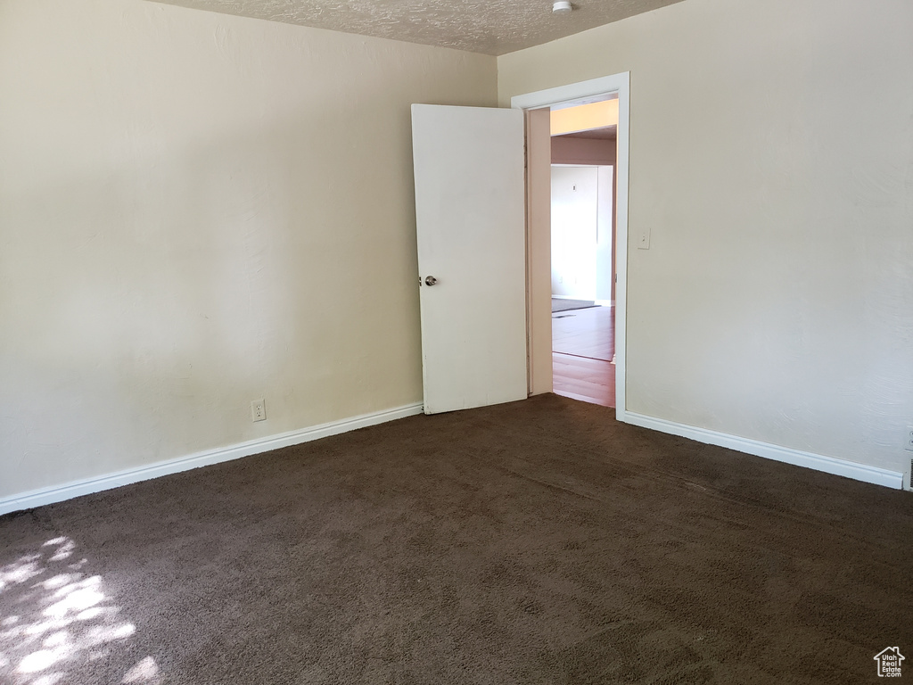 Spare room with dark colored carpet and a textured ceiling