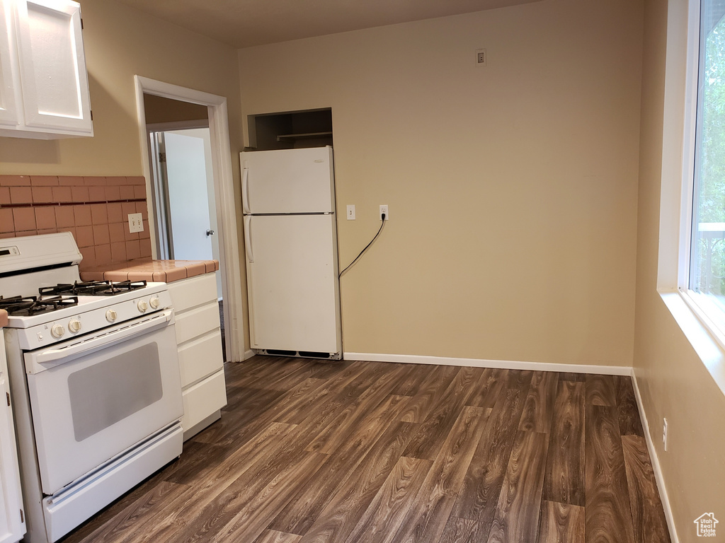 Kitchen featuring white appliances, tile counters, white cabinetry, dark wood-style floors, and decorative backsplash