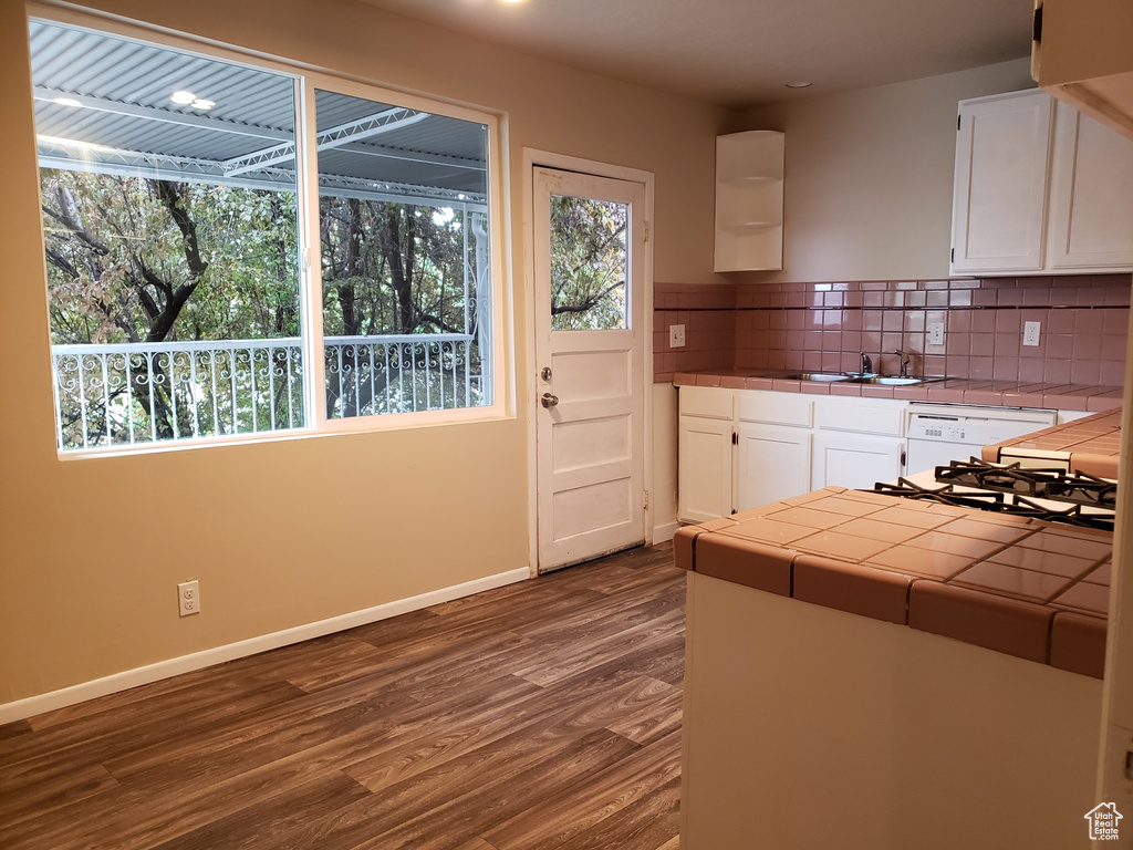 Kitchen featuring tile countertops, white cabinets, dark wood-style floors, decorative backsplash, and dishwasher