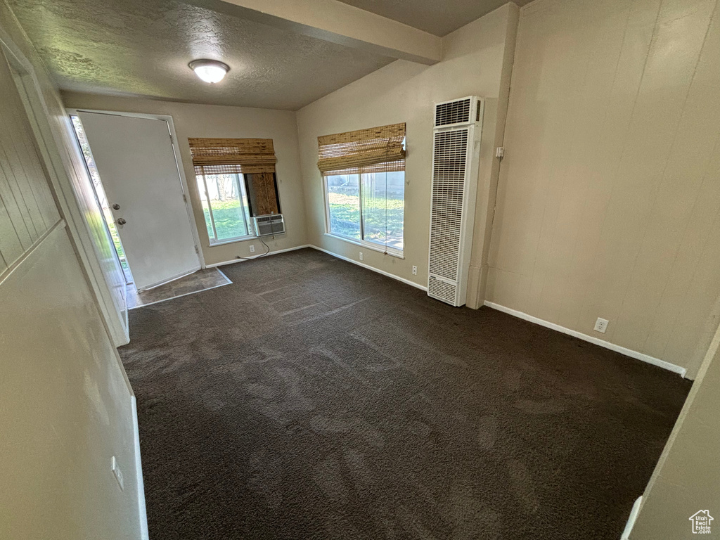 Spare room with a heating unit, dark colored carpet, a textured ceiling, and cooling unit