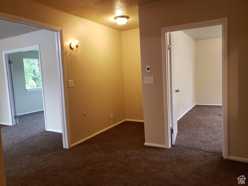 Hall featuring dark carpet and baseboards
