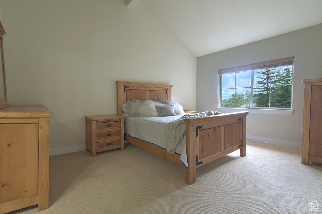 Bedroom with light colored carpet and high vaulted ceiling