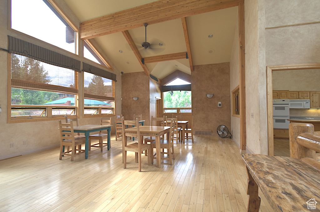 Dining space featuring high vaulted ceiling, light wood-style floors, healthy amount of natural light, ceiling fan, and beam ceiling