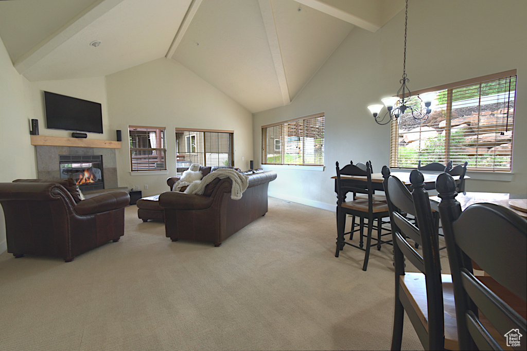 Living room featuring high vaulted ceiling, light carpet, a chandelier, a tiled fireplace, and beamed ceiling
