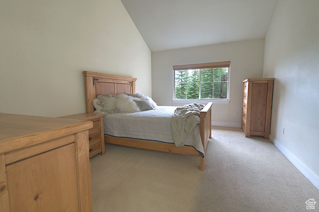 Bedroom featuring lofted ceiling and light carpet