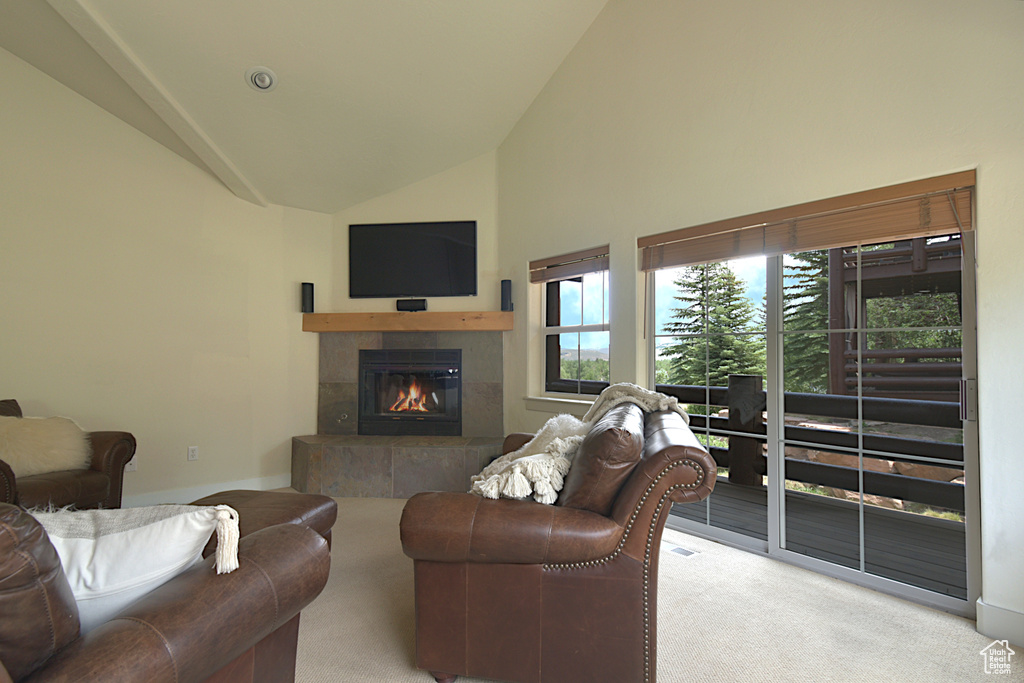 Carpeted living room with a tiled fireplace and high vaulted ceiling