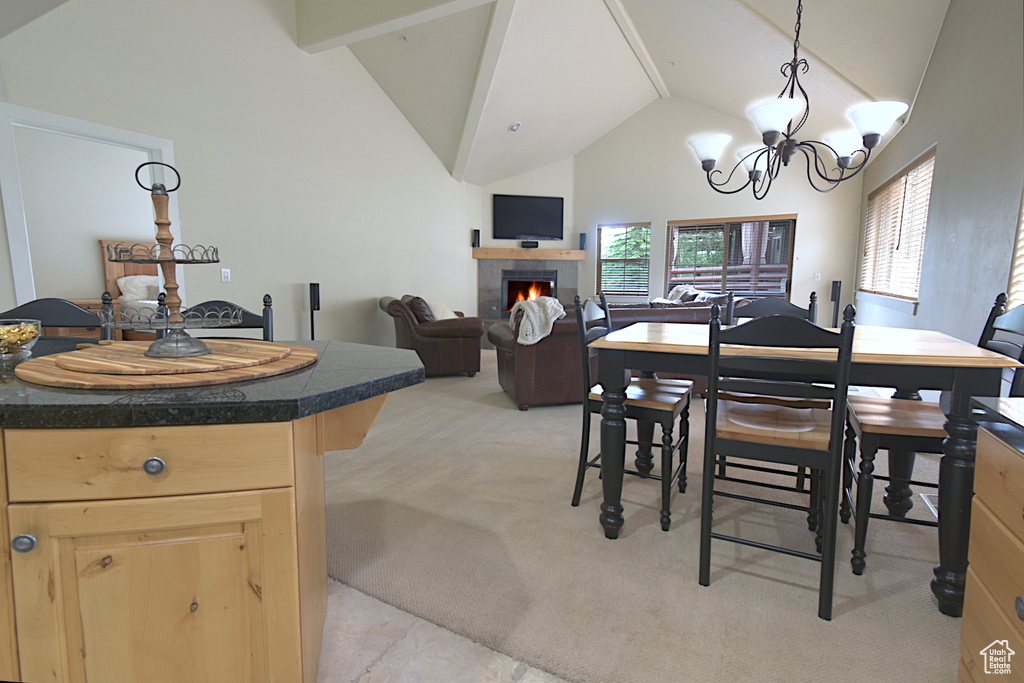 Dining area featuring a fireplace, high vaulted ceiling, light colored carpet, a chandelier, and beamed ceiling