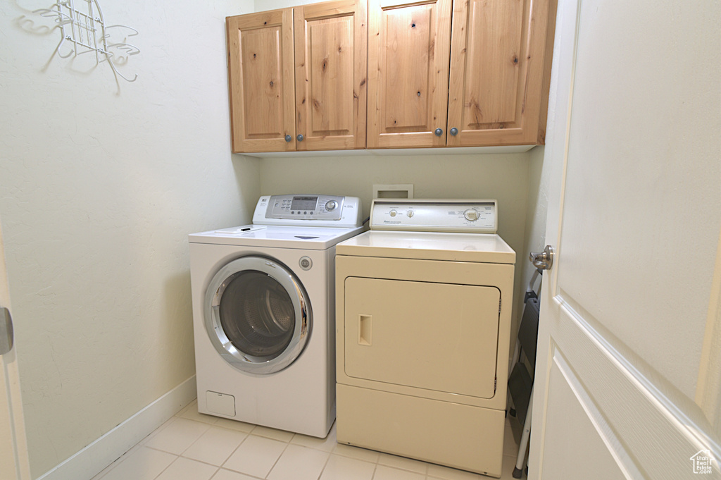 Laundry room featuring washer and clothes dryer, cabinet space, and light tile patterned floors