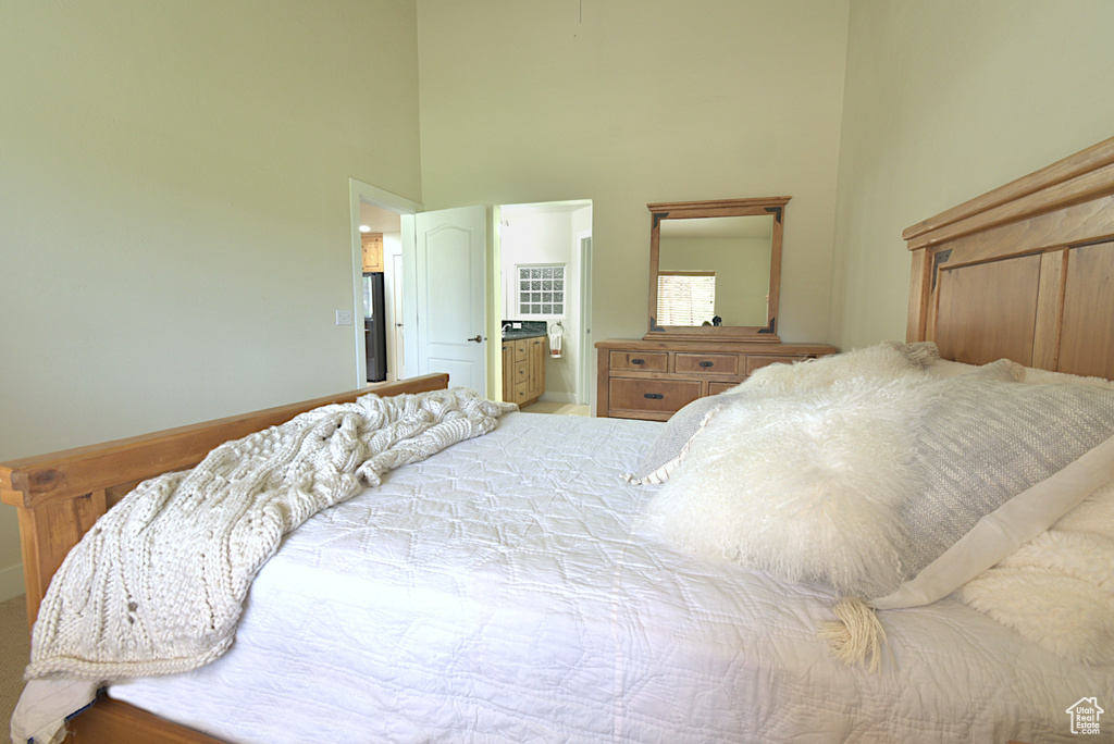 Bedroom with a high ceiling, fridge with ice dispenser, and ensuite bath