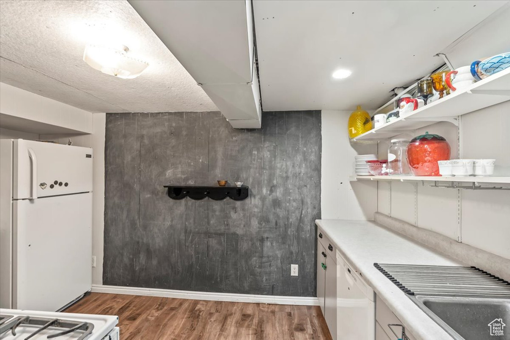 Kitchen with white appliances, wood finished floors, open shelves, and light countertops