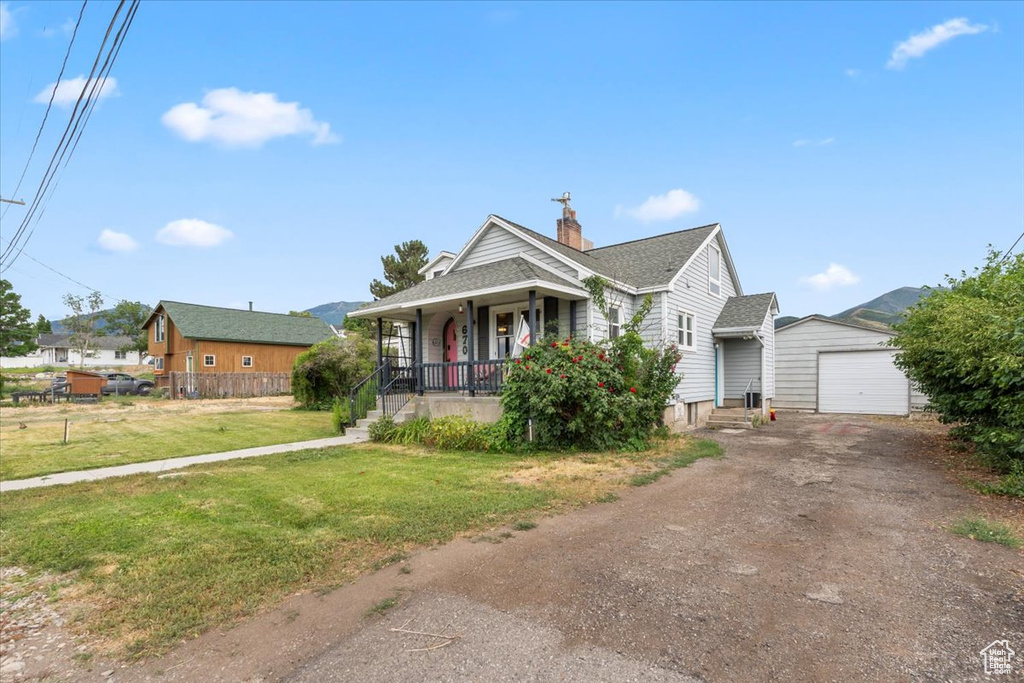 Bungalow-style home featuring a porch, driveway, a garage, a chimney, and an outdoor structure