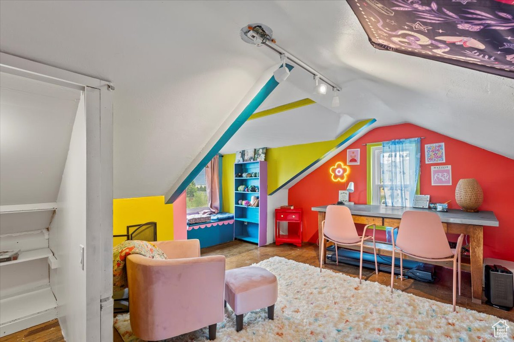 Rec room with lofted ceiling, track lighting, and a desk