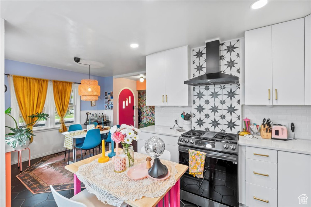 Kitchen with stainless steel gas stove, wall chimney range hood, light countertops, tasteful backsplash, and recessed lighting