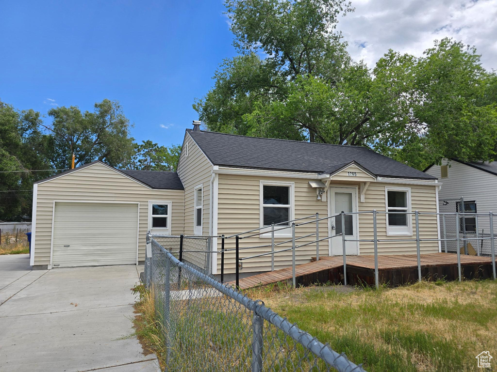 View of front of house with an attached garage, concrete driveway, a shingled roof, and a deck
