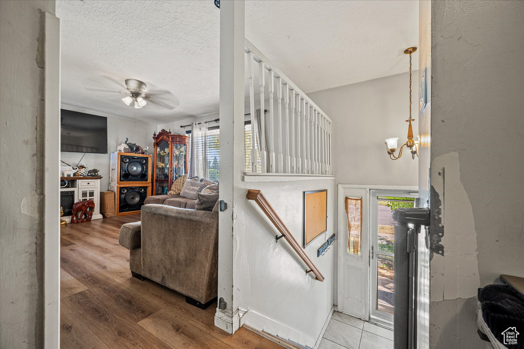 Living room featuring plenty of natural light, wood finished floors, ceiling fan, a chandelier, and a textured ceiling