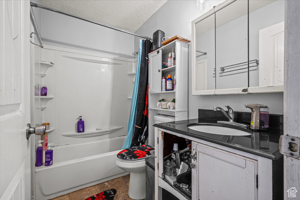 Bathroom with vanity, shower / bathtub combination with curtain, and a textured ceiling