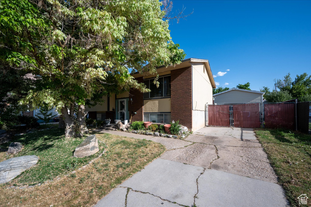View of front of home with brick siding, a gate, and asphalt driveway