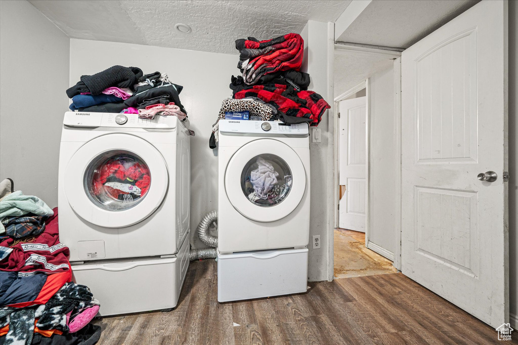 Washroom featuring washer and clothes dryer, wood finished floors, and a textured ceiling