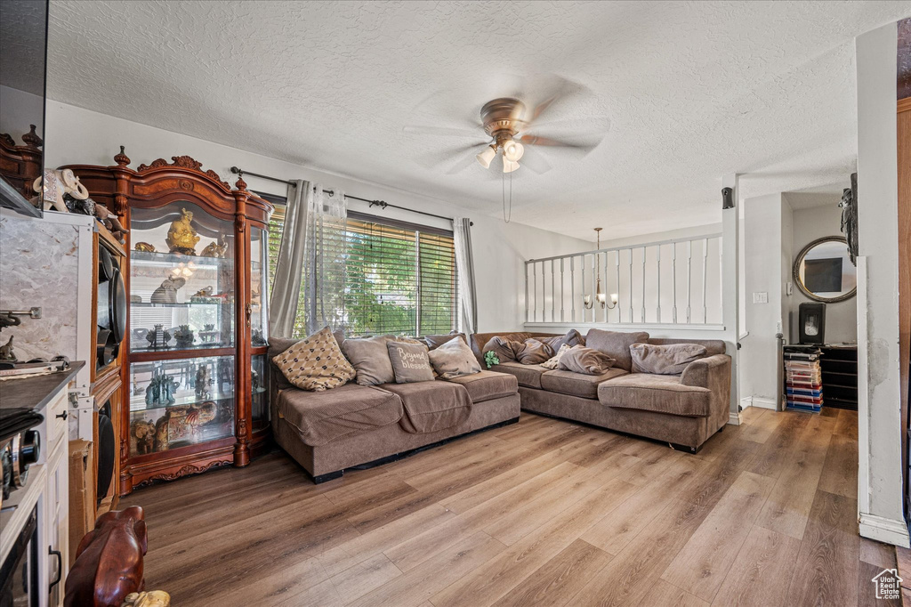 Living area with a ceiling fan, a textured ceiling, and light wood finished floors
