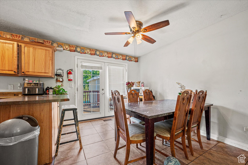 Dining room with light tile patterned floors, a ceiling fan, and a textured ceiling