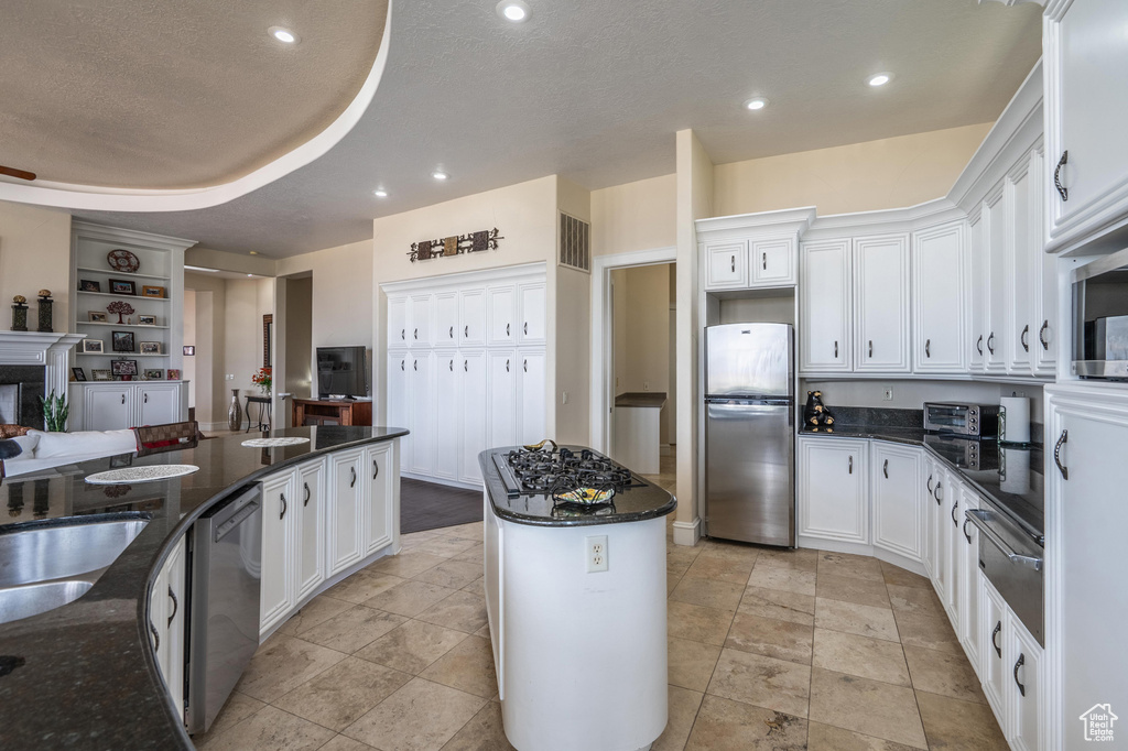 Kitchen with stainless steel appliances, white cabinetry, a center island, dark stone counters, and recessed lighting