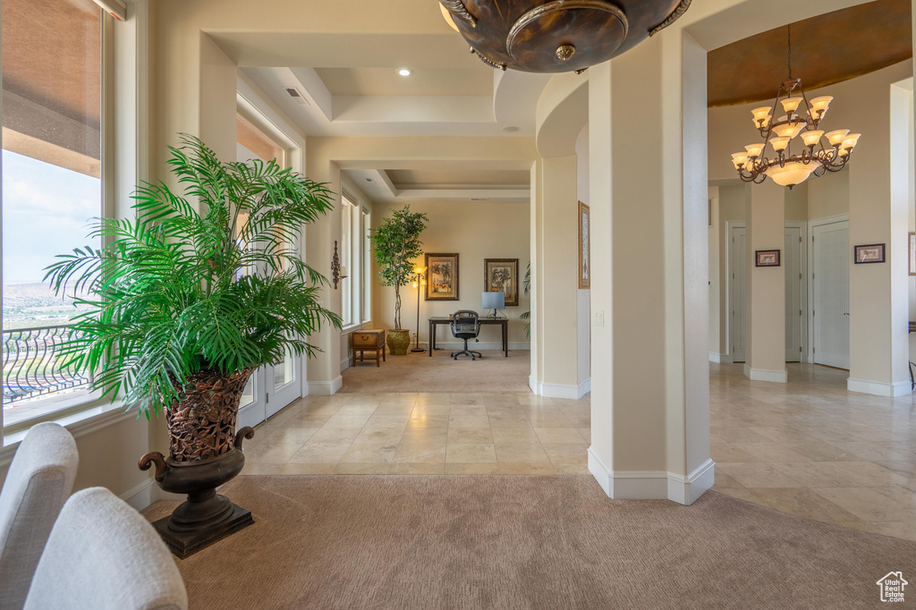Hallway featuring a tray ceiling, light tile patterned flooring, a chandelier, light carpet, and recessed lighting