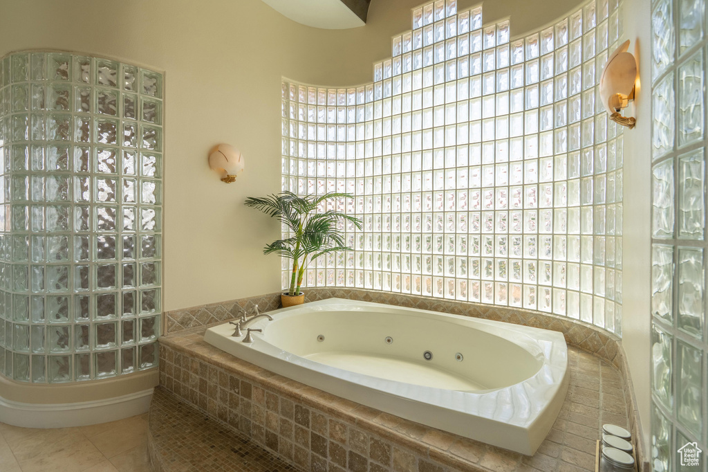 Bathroom featuring a tub with jets, healthy amount of natural light, and tile patterned flooring
