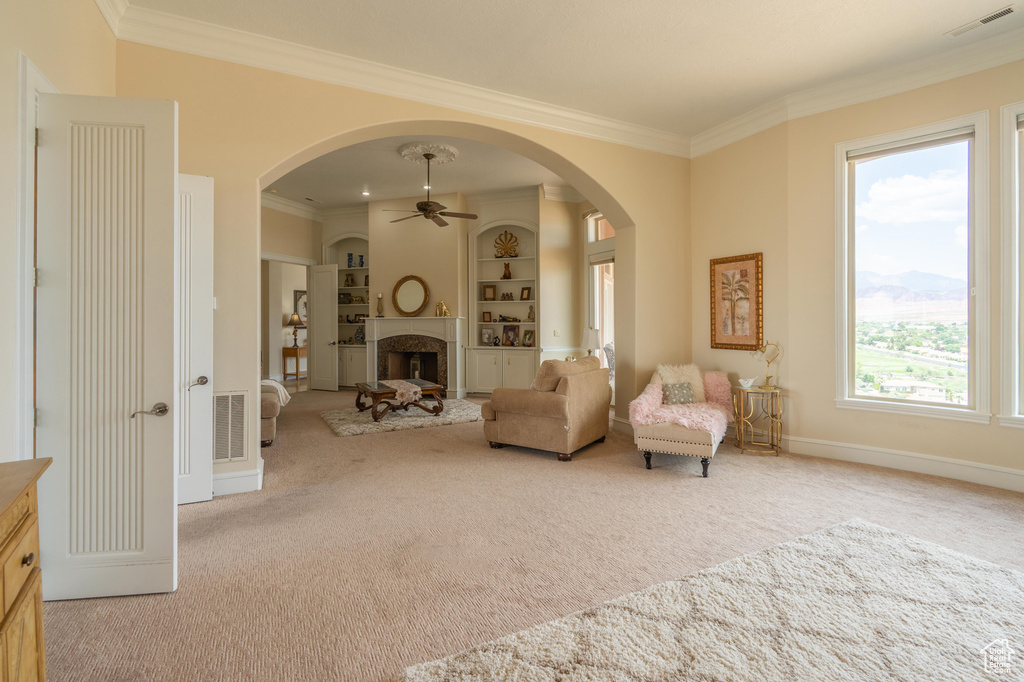 Sitting room featuring carpet, ornamental molding, ceiling fan, and arched walkways