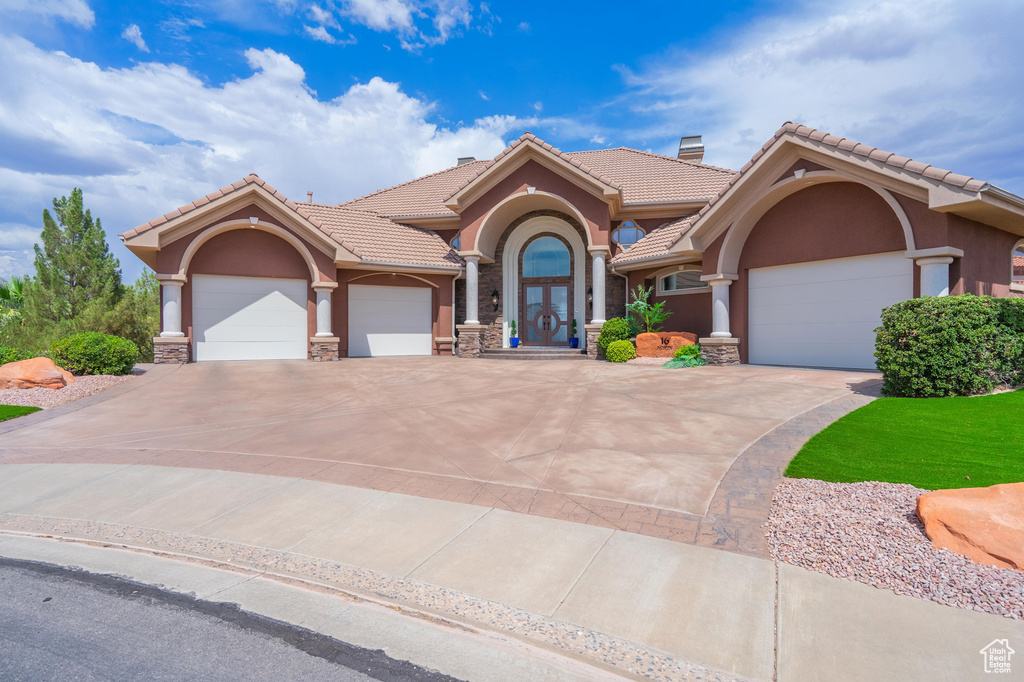 Mediterranean / spanish-style house with stucco siding, an attached garage, concrete driveway, and a tiled roof