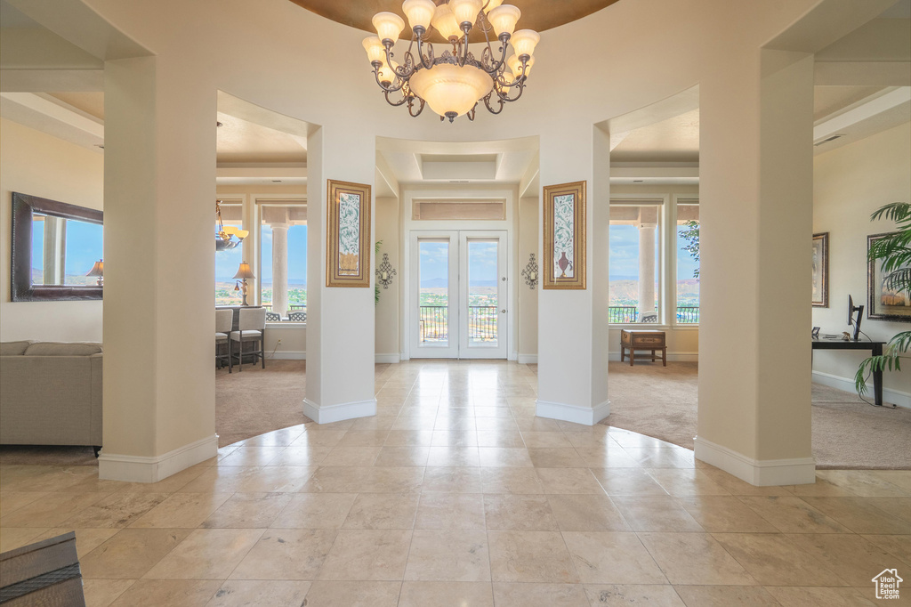 Foyer featuring plenty of natural light, light carpet, and a chandelier