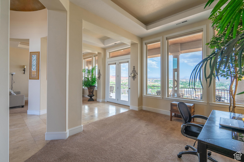 Office area with light tile patterned floors, a raised ceiling, and light colored carpet