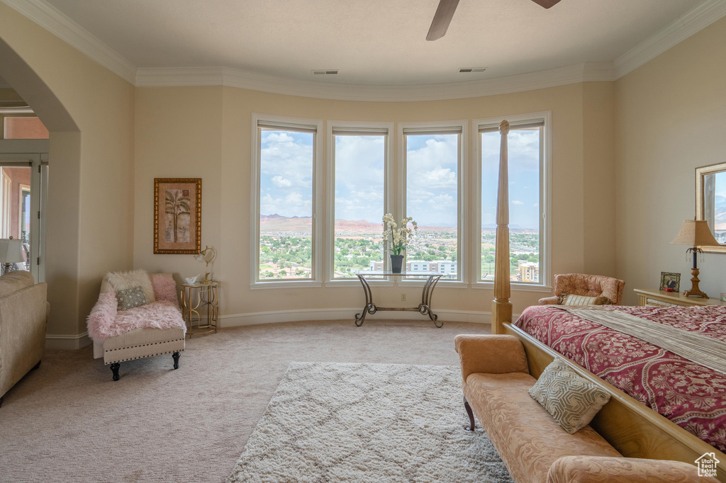 Carpeted bedroom featuring arched walkways, multiple windows, ornamental molding, and ceiling fan