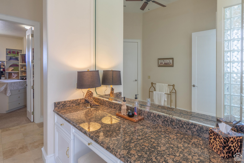 Kitchen featuring a ceiling fan, dark stone counters, and white cabinetry