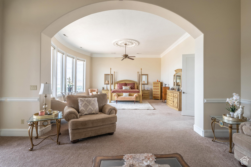 Living room with arched walkways, carpet floors, ornamental molding, and ceiling fan